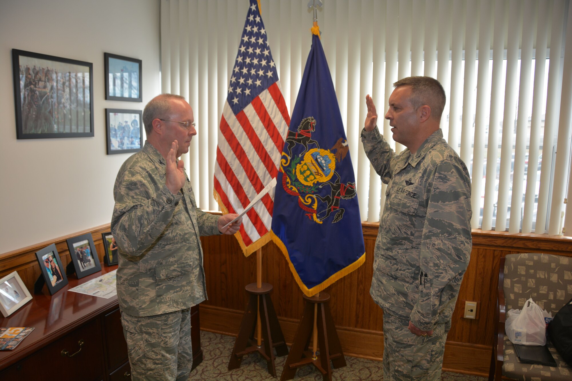 Col. Mike Cason, 193rd Special Operations Wing commander (right), raises his right hand as Col. Mike Regan, Deputy Adjutant General – Air (left), swears him into the Pennsylvania Air National Guard. Cason served as the wing commander since 2015 all while maintaining dual status as an active-duty Airman and a member of the guard – a unique position that required approval from the Secretary of Defense. He has made the decision to exit active duty and officially join the PaANG, allowing him to continue on as wing commander and provide service to the Commonwealth into the foreseeable future. (U.S. Air National Guard Photo by Senior Master Sgt. Martina Crouse/Released)