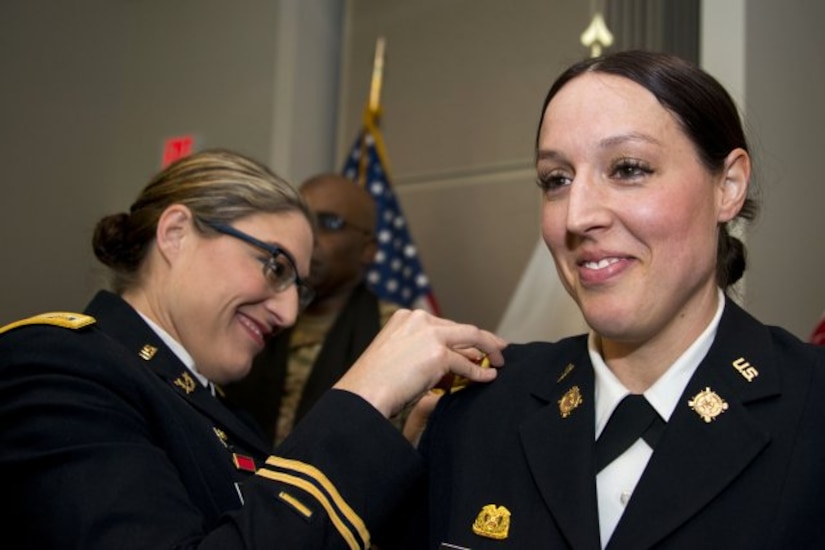 Iowa Army National Guard Maj. Jill Finkel, left, pins a new gold leaf rank insignia on Massachusetts Army National Guard Maj. Molly Alesch during her promotion ceremony at Hanscom Air Force Base, Mass., March 17, 2017. Finkel and Alesch are sisters and their youngest sister, Army Spc. Kristen Alesch, who serves in the Tennessee National Guard, also attended the promotion ceremony. Massachusetts Army National Guard photo by Sgt. 1st Class Whitney Hughes