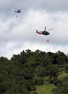 Two UH-60 Black Hawks from the California National Guard carry 600-gallon helicopter buckets and prepare for water drops April 8, 2017, at Pardee Reservoir, Ione, California, during the 2017 Wildland Firefighting Training. The exercise unites the California Guard and California Department of Forestry and Fire Protection (CAL FIRE) as a method of preparing for the upcoming fire season. 