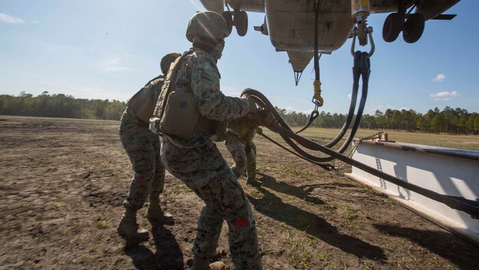 Marines attach a 1,000 pound metal beam to a CH-53E Super Stallion while conducting helicopter support team operations at Marine Corps Base Camp Lejeune, N.C., March 30, 2017. The training helped the Marines hone their skills in the transportation of gear via air assets and was part of field exercise Bold Bronco 17. The Marines are landing support specialists with 2nd Transportation Support Battalion, 2nd Marine Logistics Group. 