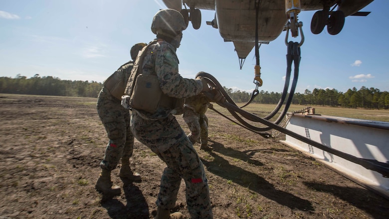 Marines attach a 1,000 pound metal beam to a CH-53E Super Stallion while conducting helicopter support team operations at Marine Corps Base Camp Lejeune, N.C., March 30, 2017. The training helped the Marines hone their skills in the transportation of gear via air assets and was part of field exercise Bold Bronco 17. The Marines are landing support specialists with 2nd Transportation Support Battalion, 2nd Marine Logistics Group. 