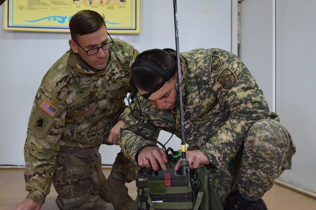Staff Sgt. William Gordley, 149th Military Engagement Team, observes a Kazakhstani signal soldier who races against time to prepare his radio and send a radio check during Steppe Eagle Koktem Apr. 4, 2017, at Illisky Training Center, Kazakhstan. Tactical communications is one of the military-to-military engagements that occur during Koktem.