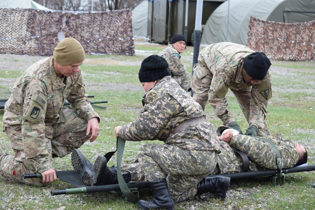 Two U.S. Army Soldiers from 3rd Medical Command (Deployment Support) assist a Kazakhstani medic with a litter while practicing patient loading into an ambulance during Steppe Eagle Koktem Apr. 3, 2017, at Illisky Training Center, Kazakhstan.