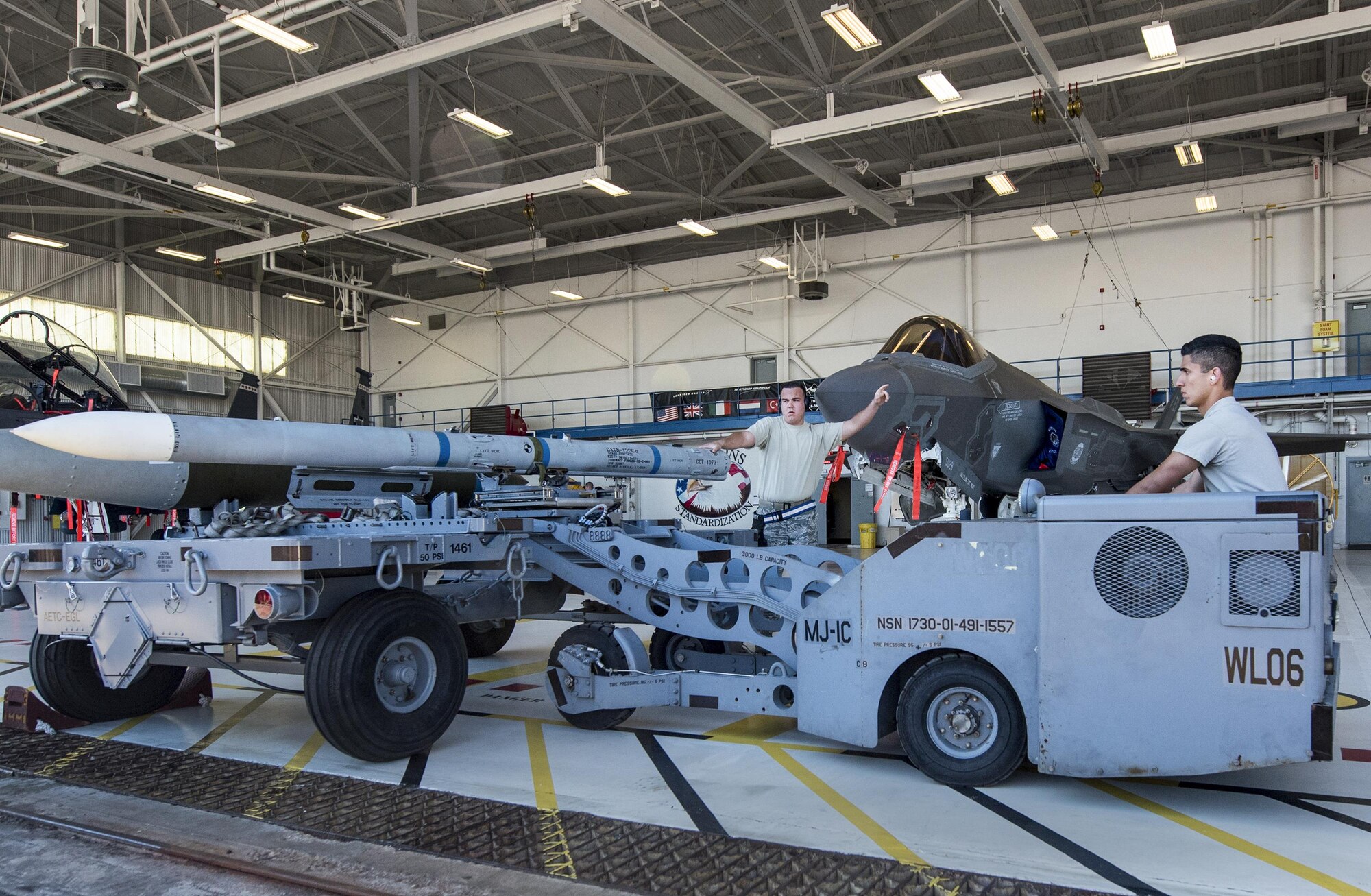 Staff Sgt. Brody Bundy, 33rd Aircraft Maintenance Squadron, directs an AIM-120 missile toward an F-35 during the Team Eglin weapons load competition April 7 at Eglin Air Force Base, Fla.  Teams from the 33rd Fighter Wing and 96th Test Wing competed to see who could load up two weapons onto their designated aircraft the quickest and with the fewest errors.  The 33rd FW team repeated as base champion.  (U.S. Air Force photo/Samuel King Jr.)