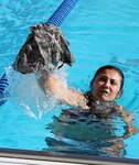 1st Lt. Heather De La Cruz, a Soldier with the 505th Military Intelligence Brigade (Theater), throws her uniform blouse out of the pool while she treads water during the German Armed Forces Proficiency Badge event at JBSA- Fort Sam Houston March 31. De La Cruz won gold in the event.