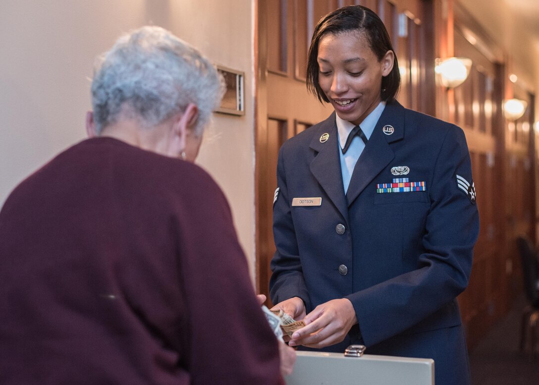 Senior Airman Amanda Dotson, 779th Medical Support Squadron services journeyman, collects money for a ticket from an attendee of the National Prayer Luncheon at Joint Base Andrews, Md., April 4, 2017. The event consisted of group prayer, a meal, music by the U.S. Air Force Band, and a speech made by Brig. Gen. J. Steven Chisolm, Air National Guard Assistant to the U.S. Air Force Chief of Chaplains. (U.S. Air Force photo by Senior Airman Jordyn Fetter)