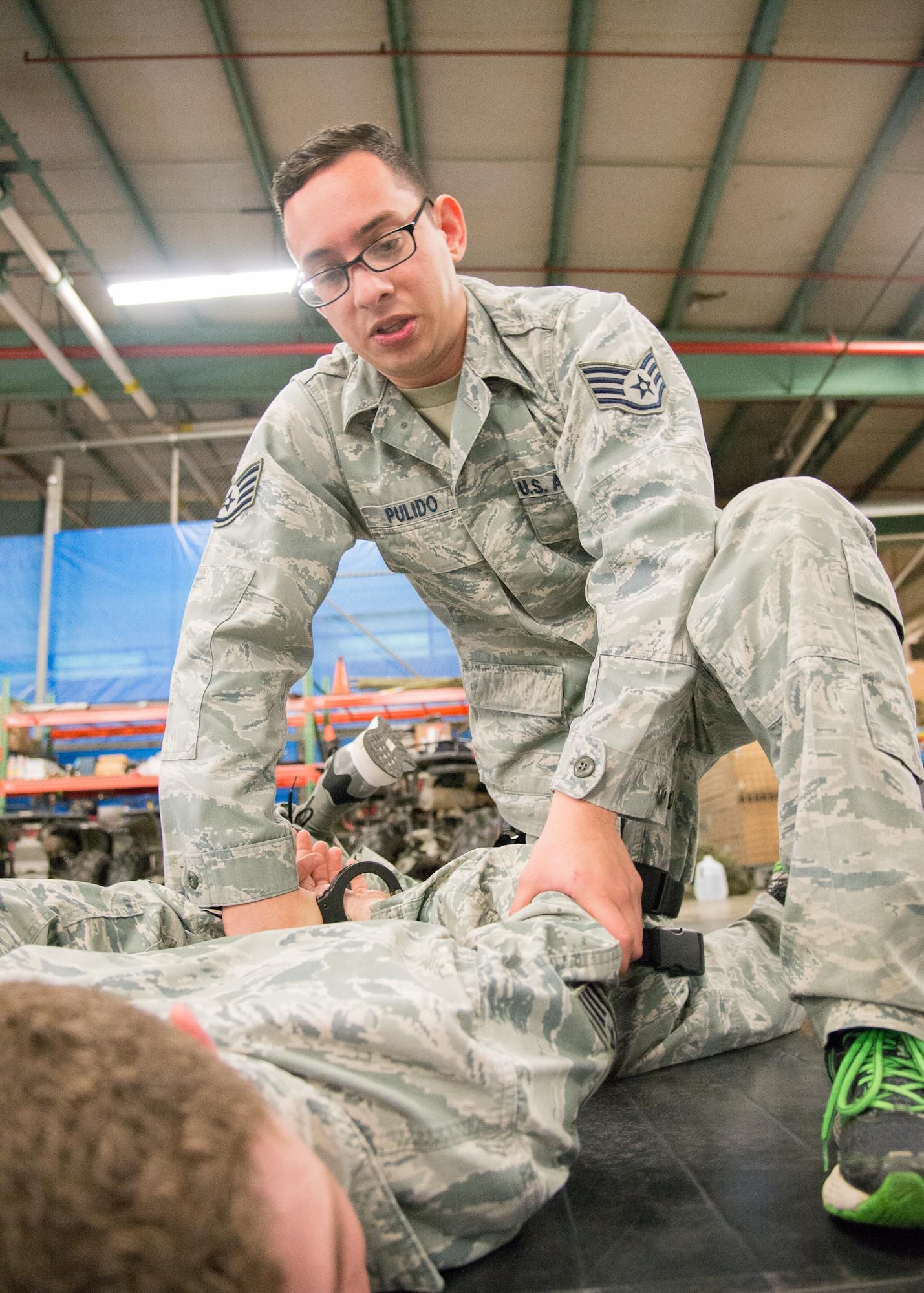 Staff Sgt. Jeffrey Pulido, 436th Security Forces Squadron trainer, practices handcuffing a suspect in the prone position and then assisting them to their feet April 6, 2017, at Dover Air Force Base, Del. Pulido was one of 12 Dover AFB security forces members who honed their skills during a recent training session with 30 Delaware State Police Officers. (U.S. Air Force photo by Mauricio Campino)