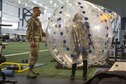 U.S. Air Force Airman Anthony Anderson, a 354th Force Support Squadron fitness specialist, explains how to use a knocker ball to Cassadee Pope April 8, 2017, at Eielson Air Force Base, Alaska. Anderson gave Pope a tour of the Baker Field House and explained the services it provides for the Iceman Team. (U.S. Air Force photo by Airman 1st Class Cassandra Whitman)