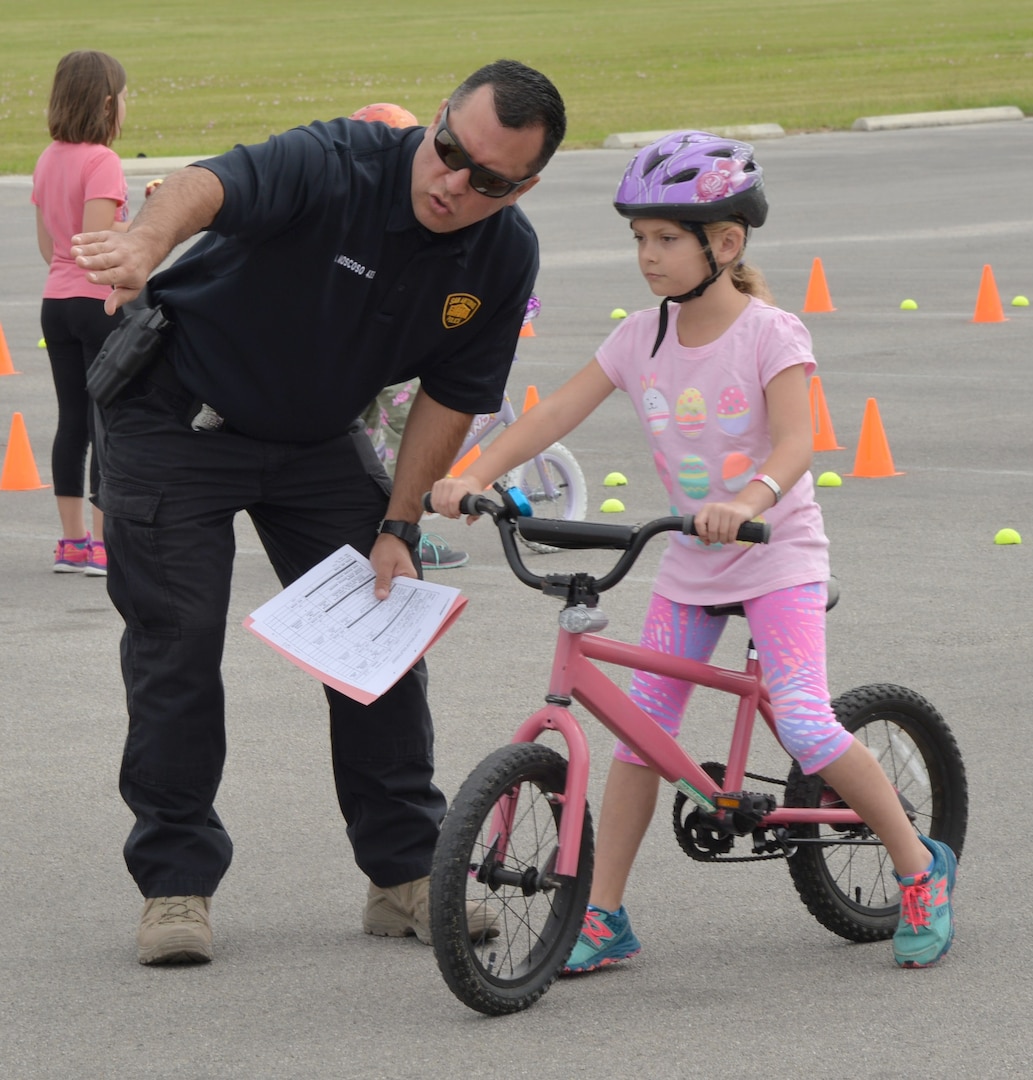 Officer W. Moscoso, San Antonio Police Department, instructs 8-year-old Kathryn Huisken on how to start and what to do in the obstacle course at the 2017 Spring Bike Rodeo on April 8 at Joint Base San Antonio-Fort Sam Houston.  Parents and children were shown  a safety video by the San Antonio Police Department before riding their bikes. SAPD Officers and Explorers, Bexar County Sheriff Motorcycle Traffic Controllers and the 502nd Security Forces Squadron, provided educational, encouragement and enforcement programs that support bicycling in San Antonio at the 2017 Spring Bike Rodeo.