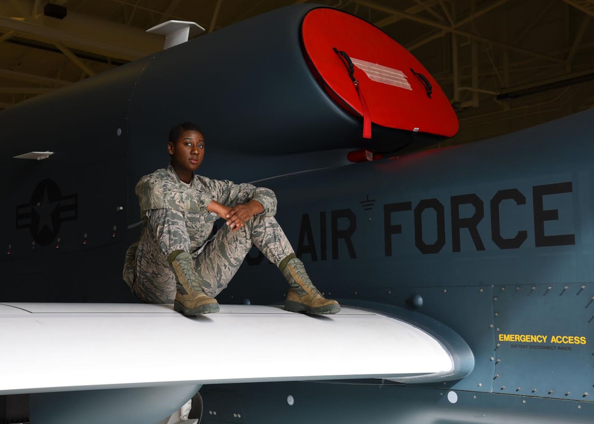 Airman 1st Class Celeste Black, a crew chief with the 69th Maintenance Group, demonstrates how strong the wings of the RQ-4 Global Hawk are by sitting on one at Grand Forks Air Force Base, N.D. March 28, 2017. Black said she has yet to deploy to work on the Global Hawk overseas because of her fight with cancer, but hopes to be able to soon. (U.S. Air Force photo by Airman 1st Class Elora J. McCutcheon