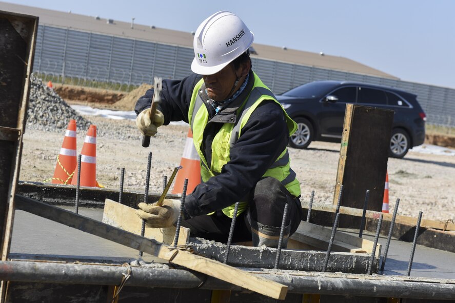 A Republic of Korea contractor hammers rebar into wet cement at Kunsan Air Base, Republic of Korea, March 21, 2017. The structure will house fuel lines that run into new flow-through shelters for the 35th Fighter Squadron at Kunsan. (U.S. Air Force photo by Senior Airman Michael Hunsaker/Released) 