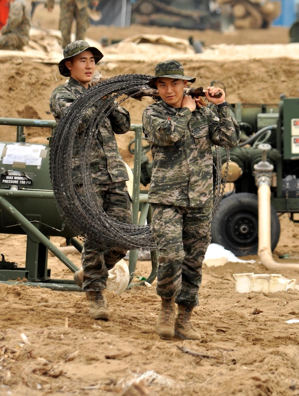 Two members of the Republic of Korea Marine Corps carry a roll of concertina wire across Dogu Beach near the South Korean port city of Pohang, April 6, 2017, as they help prepare for Operation Pacific Reach Exercise 2017. The exercise, also known as OPRex17, is a bilateral training event designed to ensure readiness and sustain the capabilities which strengthen the ROK-U.S. alliance. (Combined Forces Command photo by Sgt. 1st Class John Queen/released)

