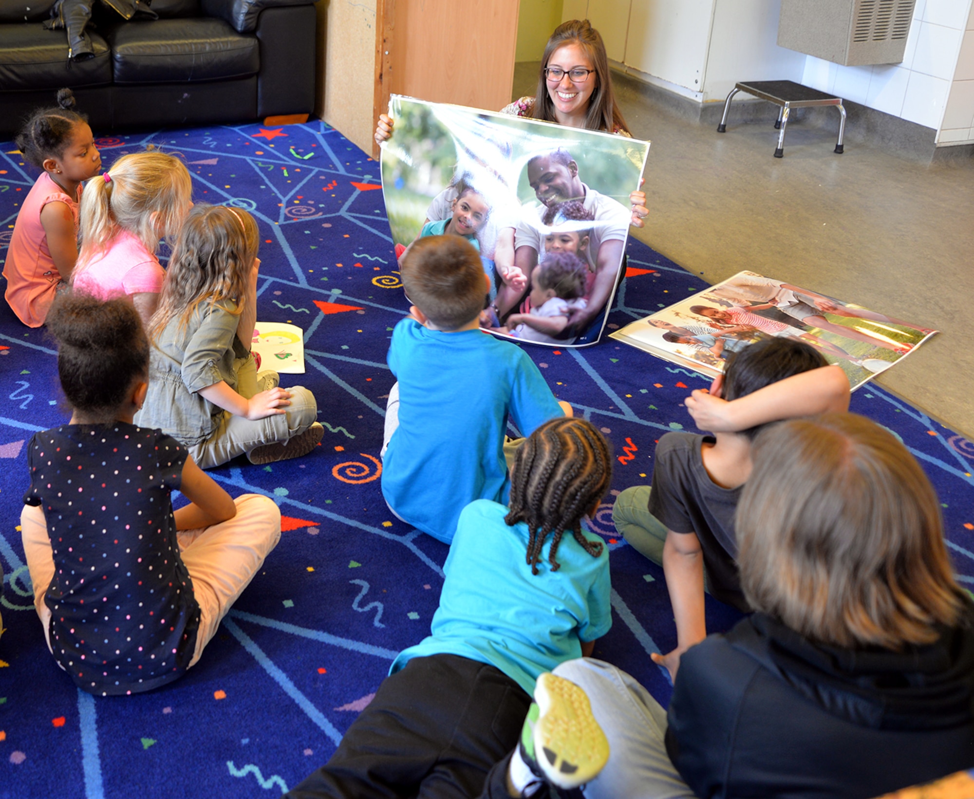 Kayla Varga, 48th Medical Operations Squadron Family Advocacy outreach manager and social worker, talks to children about healthy family dynamics and how to identify positive and negative emotions by showing them pictures at the Child Abuse Prevention Month event April 5, 2017, at the youth center on RAF Mildenhall, England. Thirty-two children, aged 5 to 12, drew pictures of their own families and friends and told Vargas what makes them happy or sad. (U.S. Air Force photo by Karen Abeyasekere)