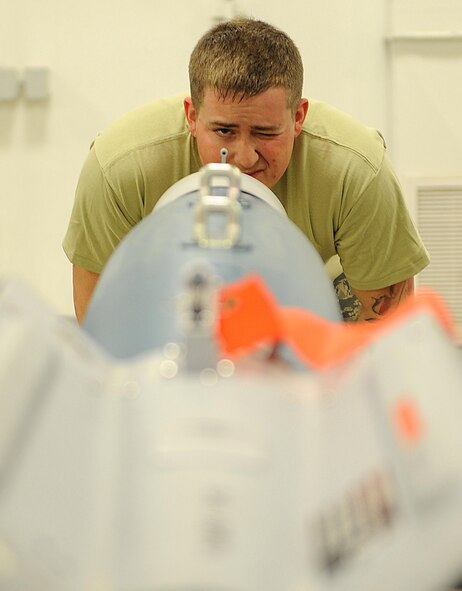 Senior Airman Collin Eaton, 5th Munitions Squadron conventional maintenance technician, looks through a tab on an inert GBU-12 bomb at Minot Air Force Base, N.D., April 5, 2017. During bomb assemblies, tabs are used to assist Airmen with aligning the nose aero-surface on the bomb. (U.S. Air Force photo/Senior Airman Kristoffer Kaubisch)