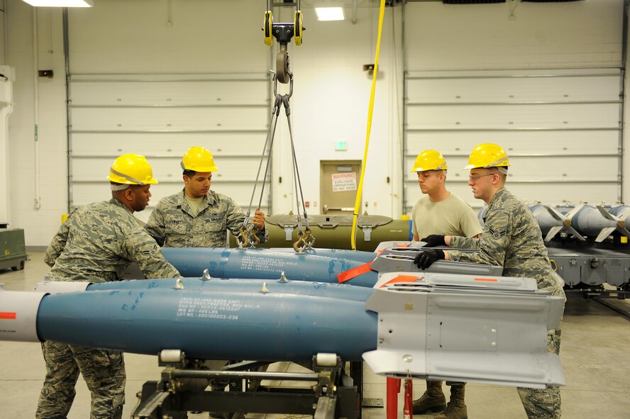 Crew members with the 5th Munitions Squadron conventional maintenance use an indoor crane to move inert GBU-12 bombs onto a rack for maintenance at Minot Air Force Base, N.D., April 5, 2017. Conventional maintenance crew members conduct familiarization and characteristic training to meet armor load standardizations. (U.S. Air Force photo/Senior Airman Kristoffer Kaubisch)