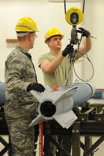 (From left) Airman 1st Class Stephen Walters and Derek Merkley, 5th Munitions Squadron conventional maintenance technicians, unhook an inert GBU-12 bomb from an indoor crane at Minot Air Force Base, N.D., April 5, 2017. Conventional maintenance crew members conduct familiarization and characteristic training to meet armor load standardizations. (U.S. Air Force photo/Senior Airman Kristoffer Kaubisch)