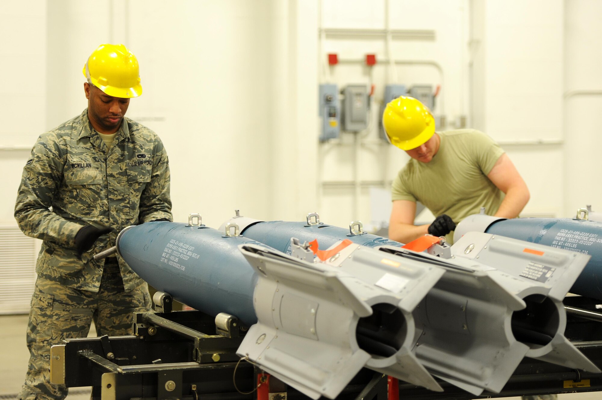 (From left) Airman 1st Class Brandon McMillan and Derek Merkley, 5th Munitions Squadron conventional maintenance technicians, replace the spanner bolt assemblies on inert GBU-12 bombs at Minot Air Force Base, N.D., April 5, 2017. Situational awareness and teamwork is crucial for safe and effective transport of weapons systems on base. (U.S. Air Force photo/Senior Airman Kristoffer Kaubisch)