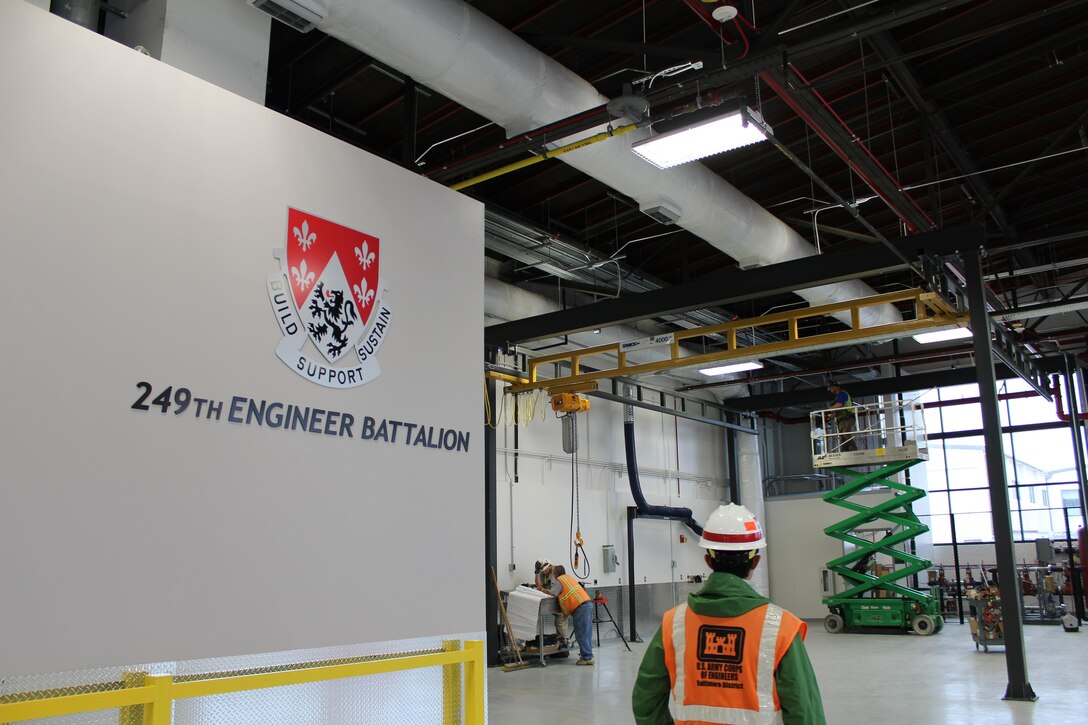 Project Engineer Nhat Tran, from the U.S. Army Corps of Engineers, Baltimore District, inspects the nearly finished renovation work inside Building 1417, April 6, 2017, as contractors look over blueprints away from the finishing up of the construction activities. Building 1417 is used by the 249th Engineer Battalion (Prime Power) for maintenance on generators and vehicles as well as storage and other activities.