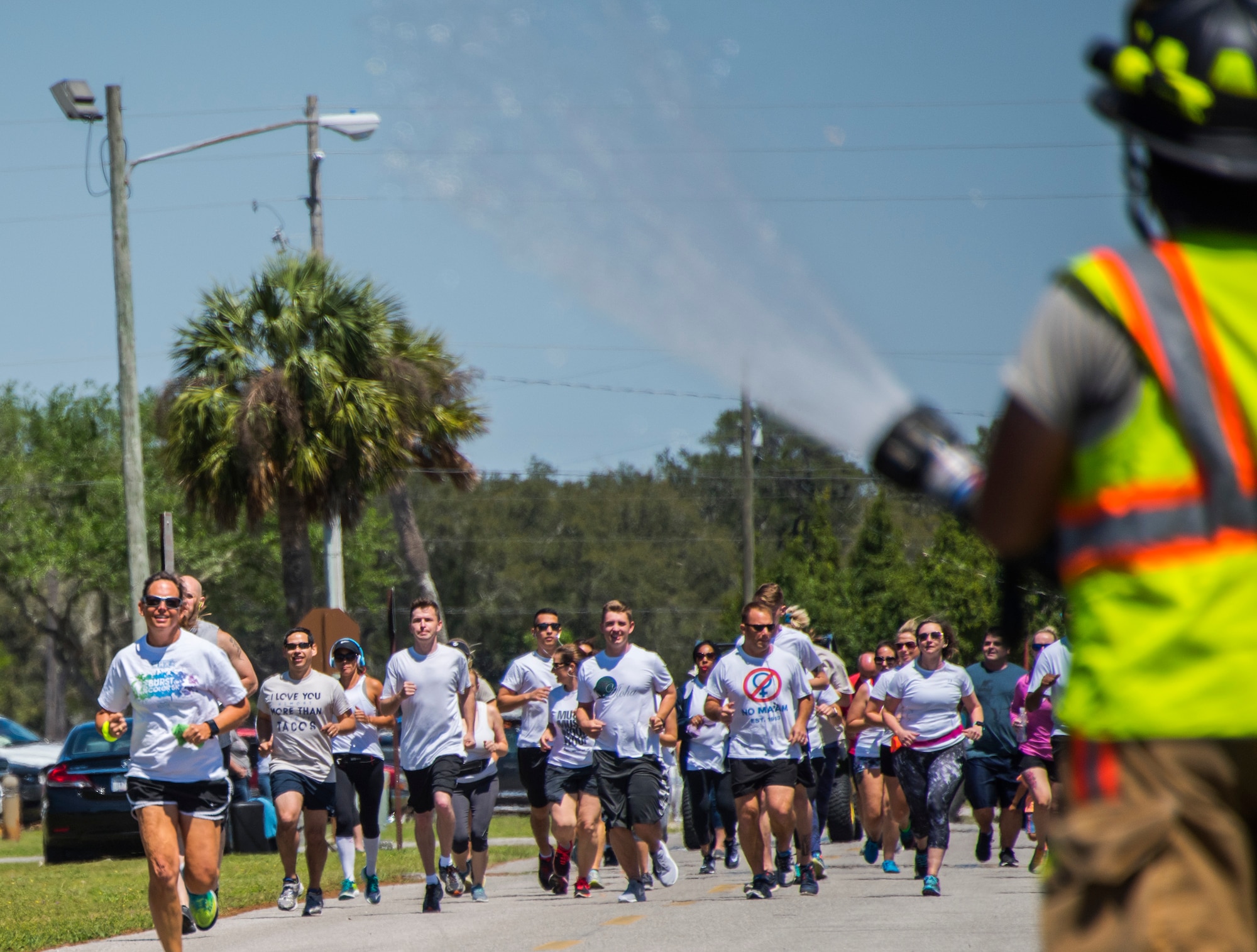 A firefighter sprays water on run participants during the 4th annual Color Me Aware Fun Run April 6 near the Civil Engineer Pavilion at Eglin Air Force Base, Fla. The run is held to raise sexual assault awareness. (U.S. Air Force photo/Ilka Cole)