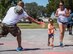 A race volunteer leans in to toss colored powder on a young runner during the 4th annual Color Me Aware Fun Run April 6 near the Civil Engineer Pavilion at Eglin Air Force Base, Fla. The run is held to raise sexual assault awareness. (U.S. Air Force photo/Ilka Cole)