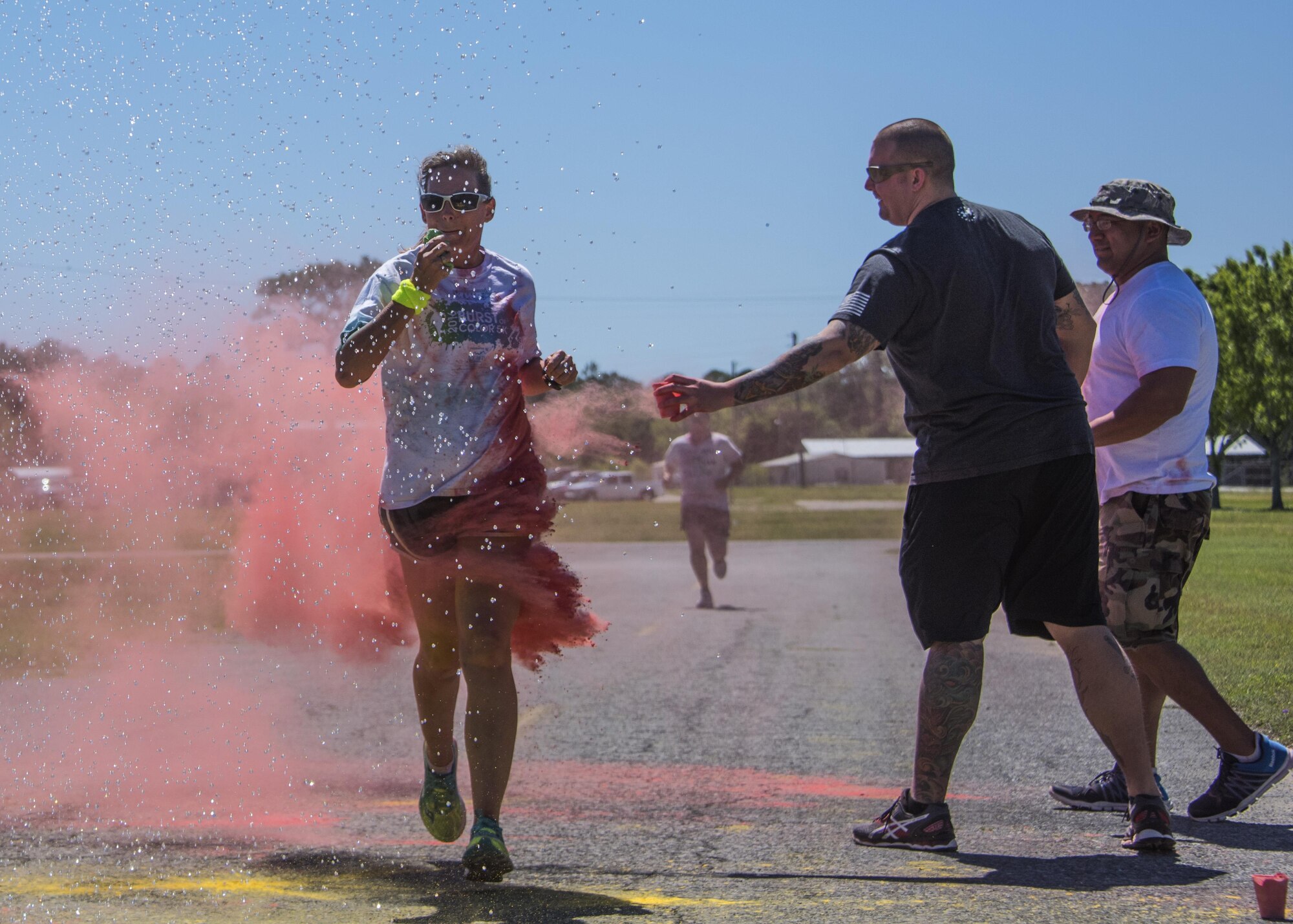 Race volunteers toss colored powder on a runner as she runs through water spray during the 4th annual Color Me Aware Fun Run April 6 near the Civil Engineer Pavilion at Eglin Air Force Base, Fla. The run is held to raise sexual assault awareness. (U.S. Air Force photo/Ilka Cole)

