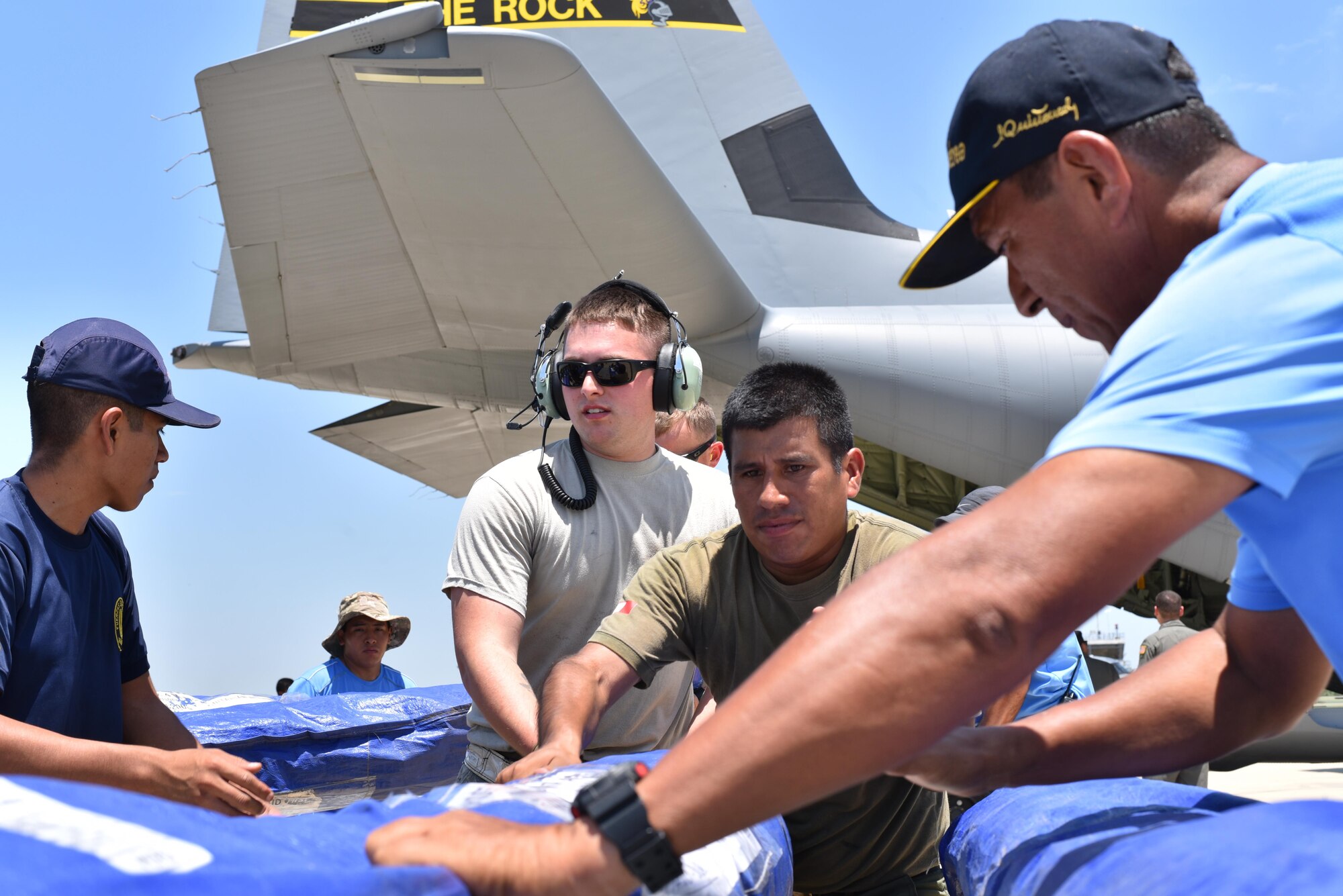 U.S. Air Force Senior Airman Dillon Roth, 41st Airlift Squadron crew chief, works alongside Peruvian Air Force members to offload tents at the airfield April 6, 2017, in Piura Peru. The 19th Airlift Wing launched two C-130Js to assist the Government of Peru to assist during a humanitarian disaster caused by unforeseen flooding and resulting landslides. (U.S. Air Force photo by Staff Sgt. Jael Laborn)