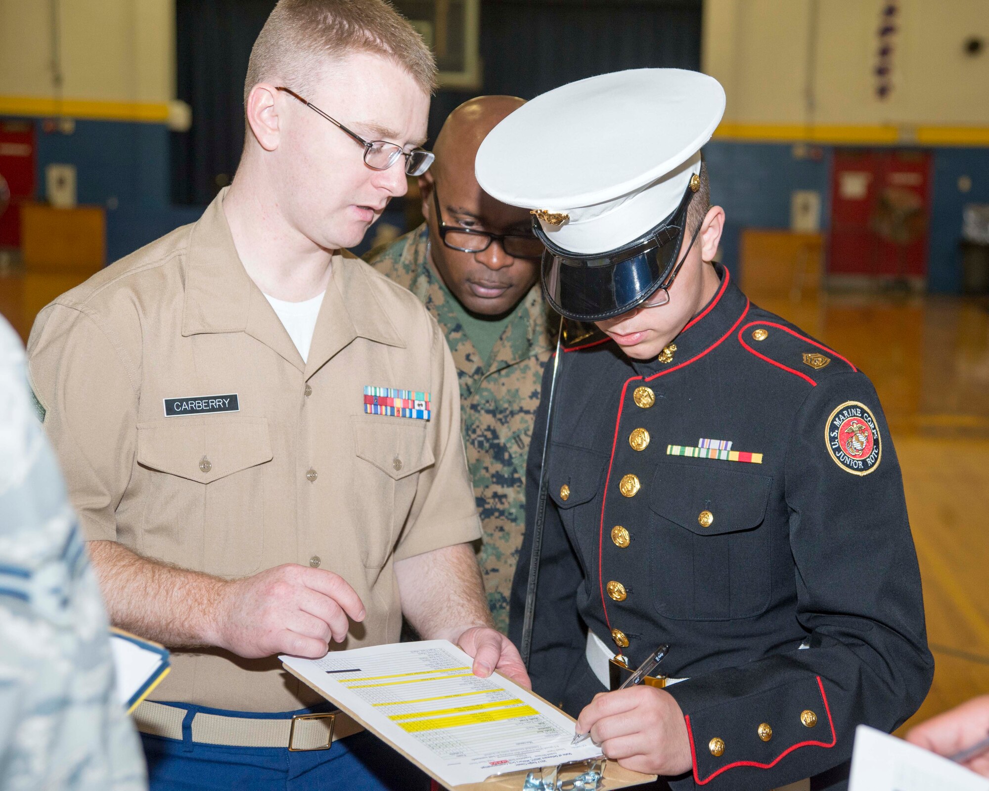 Staff Sgt. Nate Carberry, Marine recruiter, and Cadet Jordan Chesley, First State Military Academy, sign paperwork prior to the start of armed regulations during the 2017 Delaware State Junior Reserve Officer Training Corps Drill Competition April 8, 2017, on Dover Air Force Base, Del. Recruiters from the local area were asked to be judges during the competition. (U.S. Air Force photo by Staff Sgt. Jared Duhon)
