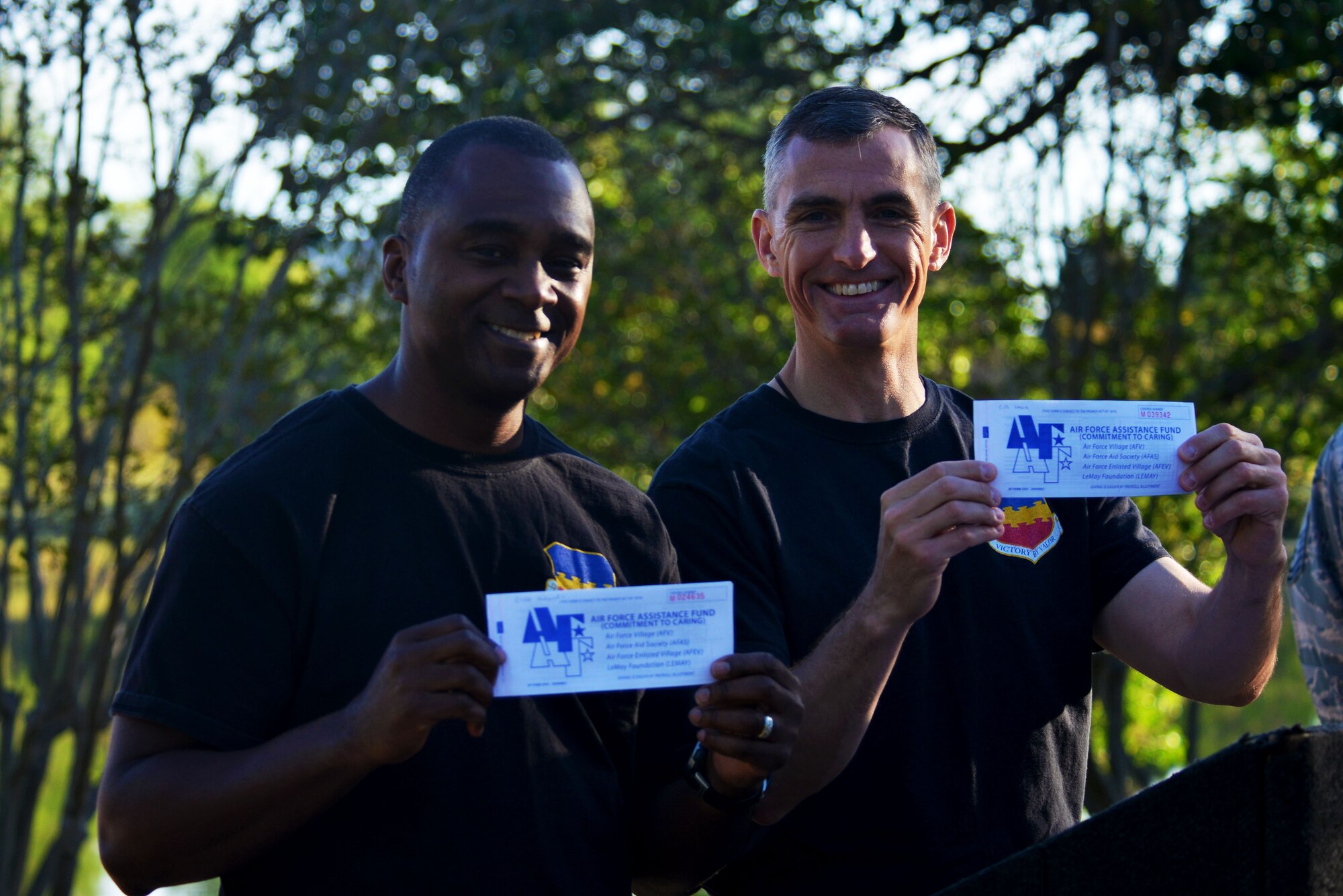 U.S. Air Force Chief Master Sgt. Christopher McKinney, 20th Fighter Wing (FW) command chief, left, and Col. Daniel Lasica, 20th FW commander, right, hold up their Air Force Assistance Fund (AFAF) donation slips during the Weasel Walk at Shaw Air Force Base, S.C., April 10, 2017. To kick off Shaw’s AFAF campaign 20th FW leadership signed donation slips toward the base’s goal of $95,153. (U.S. Air Force photo by Airman 1st Class Destinee Sweeney)