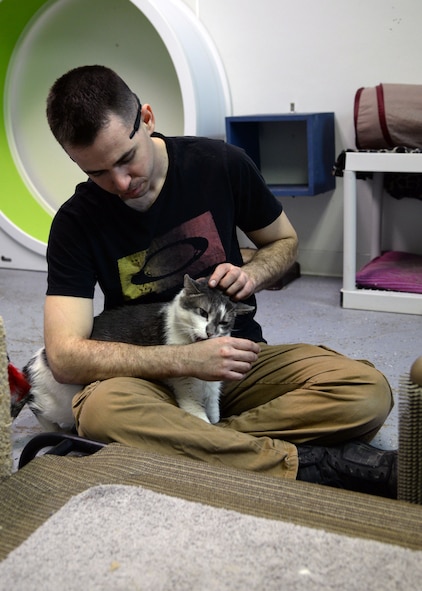 Senior Airman Frederick Vogelgesan, 5th Logistics Readiness Squadron vehicle maintainer, pets Sammie, an adult tabby cat, at the Souris Valley Animal Shelter in Minot, N.D., March 29, 2017. Vogelgesan helped care for animals and clean the facilities. (U.S. Air Force photo/Airman 1st Class Dillon J. Audit) 