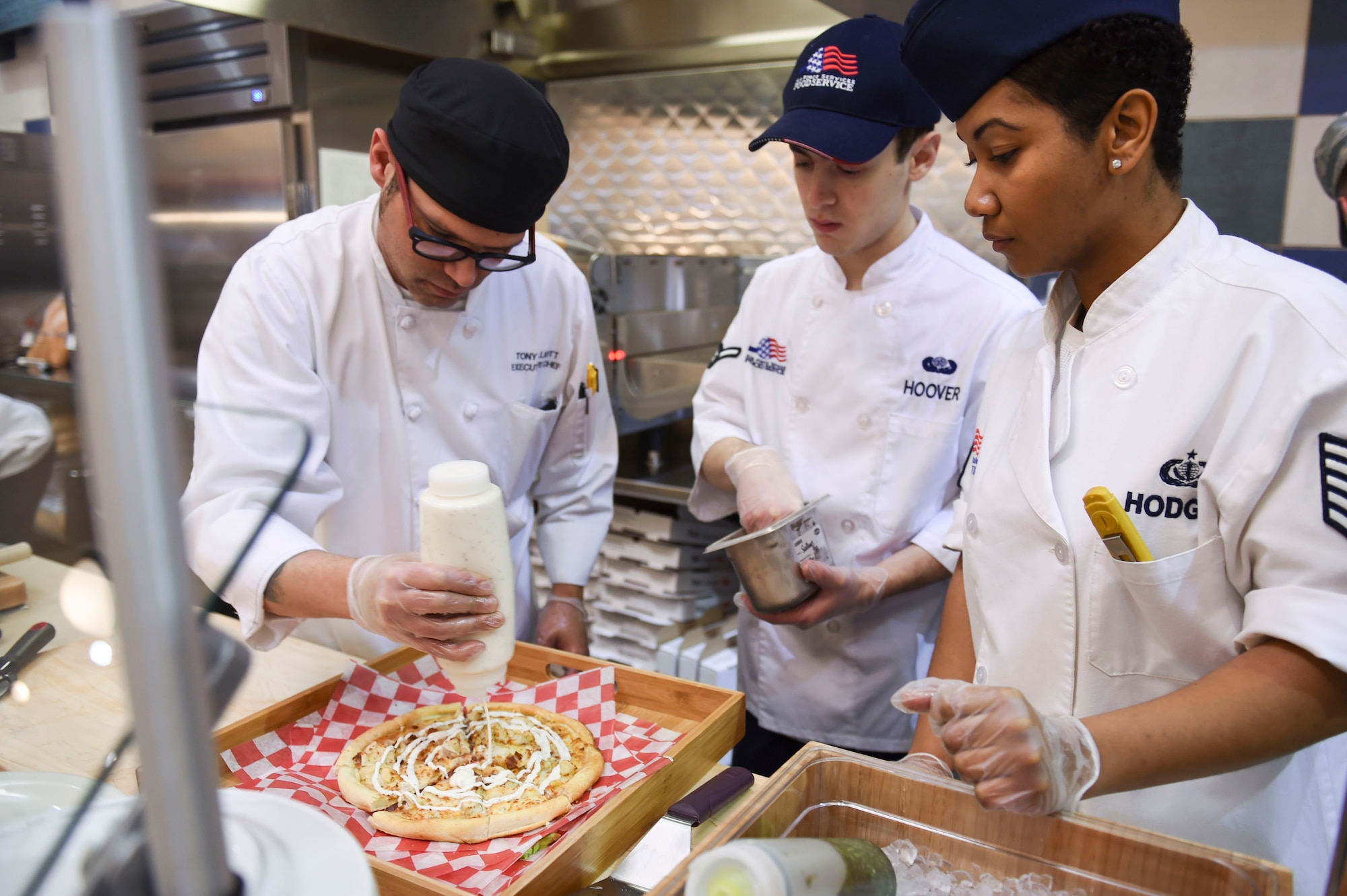 U.S. Air Force 19th Force Support Squadron dining facility Airmen and an Aramark chef prepare a personal-style pizza for sampling during the grand re-opening ceremony Jan. 23, 2017, at Little Rock Air Force Base, Ark. The pizza zone now offers made-to-order personal pan pizzas. The dining facility won the 2017 Hennessy Award Region 1 (East)for best food operation in the Air Force.(U.S. Air Force photo by Staff Sgt. Kaylee Clark)