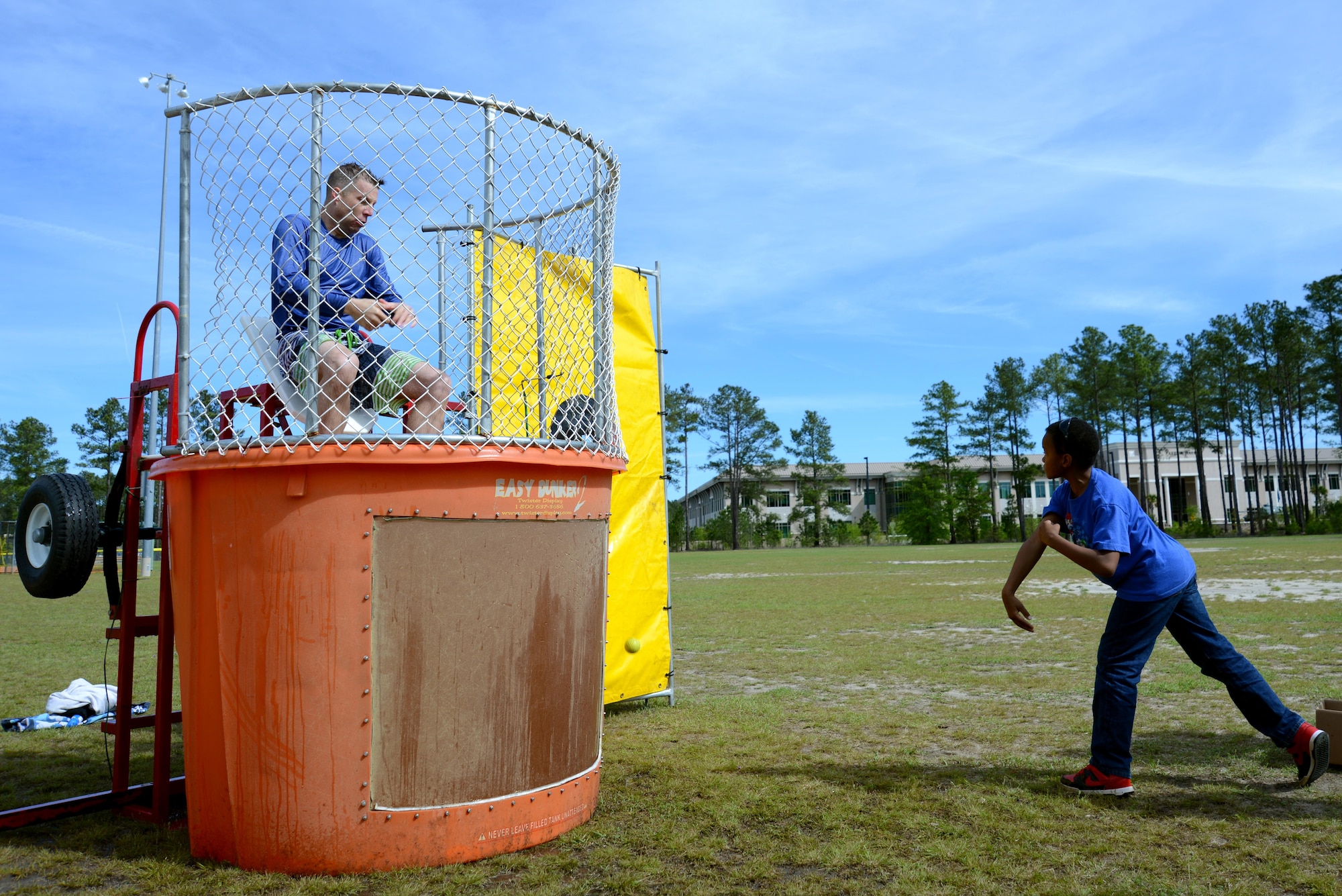 U.S. Air Force Lt. Col. William Clayton, 20th Force Support Squadron commander, left, falls into a tank of water after a Team Shaw child hits a target with a ball during a Month of the Military Child (MOMC) celebration at Shaw Air Force Base, S.C., April 8, 2017. The MOMC was first recognized in 1986 to show support for military children and highlight the sacrifices they make while their parents serve. (U.S. Air Force photo by Airman 1st Class Kathryn R.C. Reaves)