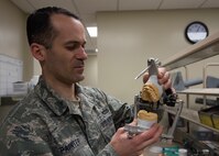 Tech. Sgt. Manuel Painter, 92nd Aerospace Medicine Squadron dental technician, displays a casting of a complete set of teeth, fixed into a jaw simulating apparatus April 07, 2017, at Fairchild Air Force Base, Wash. Creating positive molds of teeth helps dentists and technicians see how teeth will fit together. (U.S. Air Force photo/A1C Ryan Lackey)