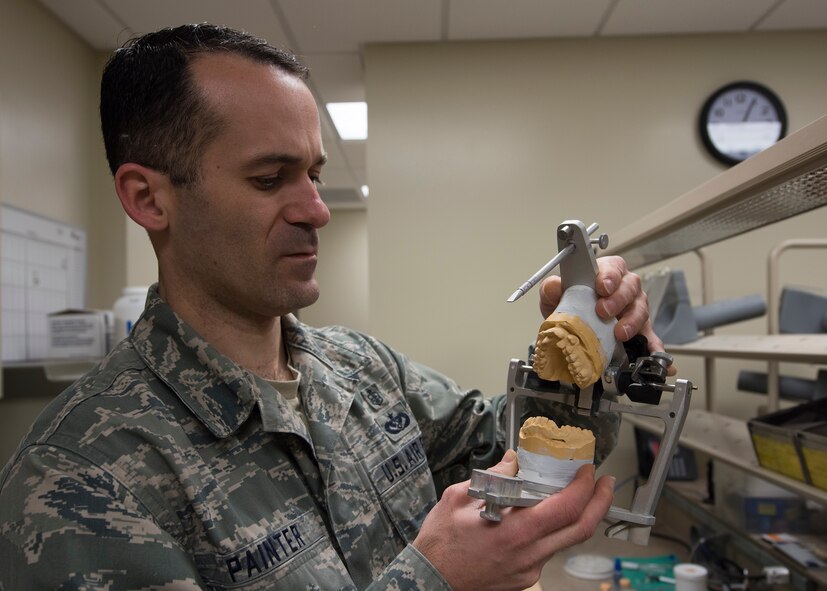Tech. Sgt. Manuel Painter, 92nd Aerospace Medicine Squadron dental technician, displays a casting of a complete set of teeth, fixed into a jaw simulating apparatus April 07, 2017, at Fairchild Air Force Base, Wash. Creating positive molds of teeth helps dentists and technicians see how teeth will fit together. (U.S. Air Force photo/A1C Ryan Lackey)