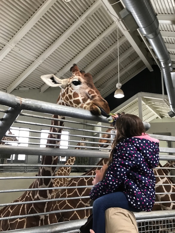 Airman 1st Class Marissa Pederson, 50 SFS entry controller, spends time with her mentee feeding giraffes during the Good Grief Camp program at the Cheyenne Mountain Zoo, Saturday, April 1, 2017.  During the two-day event, children who lost family members were paired with mentors to establish communication, maintain a military connection and to let them understand they are not alone. (Courtesy photo)