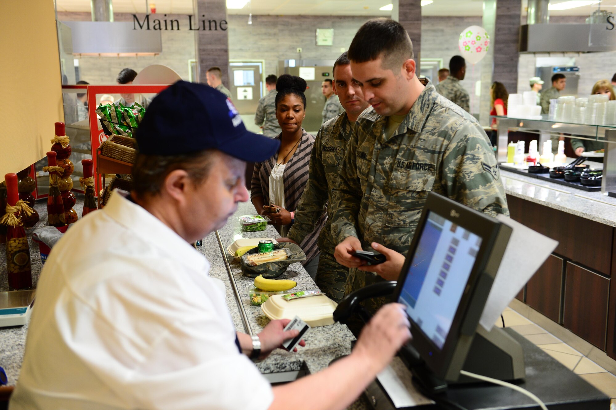 Airmen pay for their first lunch at the updated Dining Facility at Spangdahlem Air Base after several months of renovations that made meal service unavailable to the Saber community, April 10, 2017. Upgrades to the DFAC include new kitchen equipment like ovens and a walk in fridge, air conditioning installed in the kitchen, a new service line, repainting the walls and adding murals in the dining rooms to reflect the base's connection to the local community. (U.S. Air Force photo by Senior Airman Joshua R. M. Dewberry)