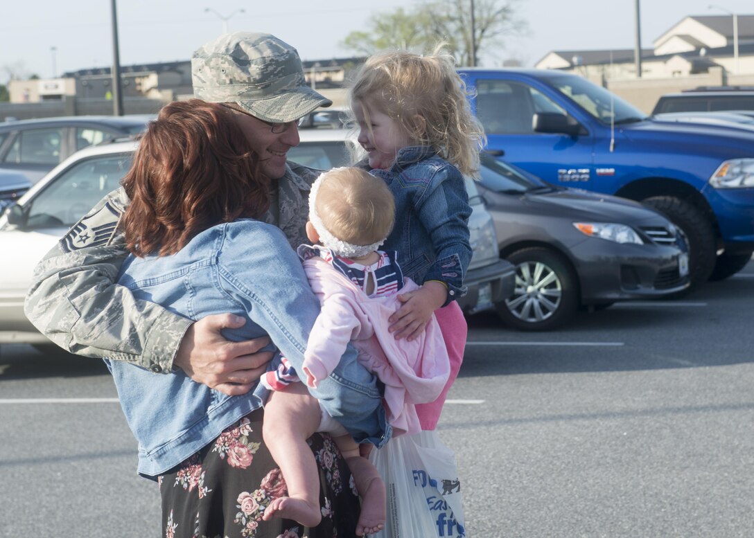 Master Sgt. Luke Young, air transportation craftsman, 46th Aerial Port Squadron, hugs his wife, Rachel, and two daughters, Melody and Emory, after returning from a 6-month deployment, April 11, 2017, Dover Air Force Base. Young deployed for 6-months to Al Udeid Air Base, Qatar. (U.S. Air Force Photo/Tech. Sgt. Nathan Rivard)