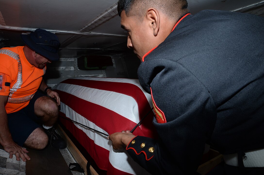 Lance Cpl. Tomas Nolasco Jr.,  Marine Corps Logistics Base Albany funeral detail member, drapes an American flag over a casket with the remains of Marine Pfc. James O. Whitehurst at the Tallahassee International Airport in Tallahassee, Fla., April 11. Whitehurst was killed in action at the battle of Tarawa during World War II, Nov. 20, 1943.