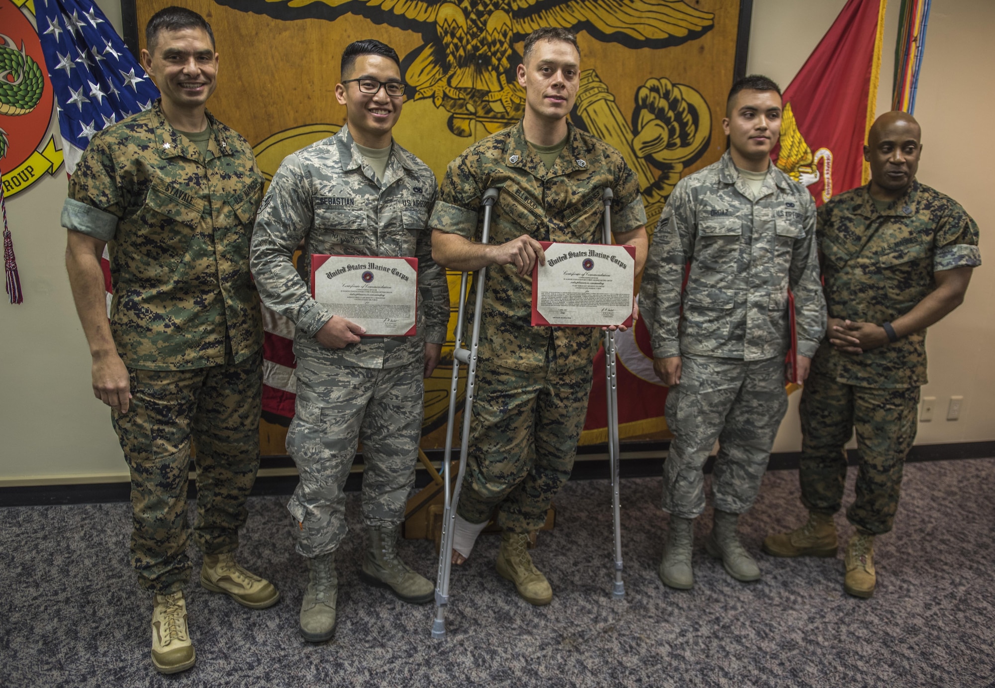 United States Marine Corp Lt. Col. Giuseppe Stavale, III Marine Headquarters Group executive officer, and Sgt. Maj. Mario Fields, III MHG sergeant major, present Airmen 1st Class Martin Sebastian and Andres Ordaz, 18th Munitions Squadron munitions systems technicians and U.S. Marine Corps Staff Sgt. Nelson Ellwood, a sub team chief with the 3rd Intelligence Battalion, awards for saving the life of a U.S. Marine Corps 1st Lt. after the lieutenant and Elwood sustained injuries during an accident at the Kadena auto hobby shop, April 7, 2017, on Camp Hansen, Japan. Thanks to the quick reactions of the two Airmen and Ellwood, the life of the lieutenant was saved after sustaining a wound resulting in a femoral bleed. (Senior Airman Nick Emerick/Released)  