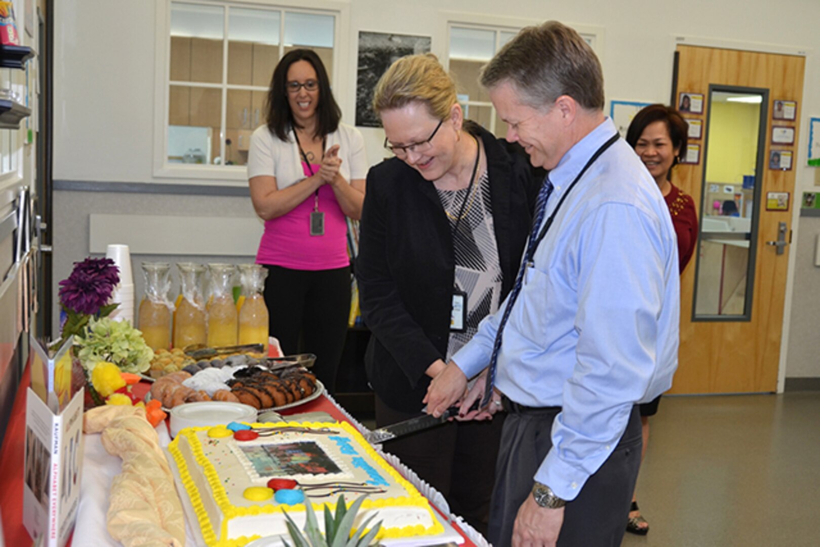 Defense Logistics Agency Installation Support at Richmond held a ceremony, April 3, 2017, for the reopening of the Bettye Akermann Cobb Child Development Center on Defense Supply Center Richmond, Virginia. In celebration David Gibson, right, director of DLA Installation Support at Richmond, and the DLA Installation Support's Director Denise Miller, center, cut the cake as CCD Director Casey Chapman, back left, and Family Morale and Wellness Director Ursula Hickox, back right, share in the celebration. 