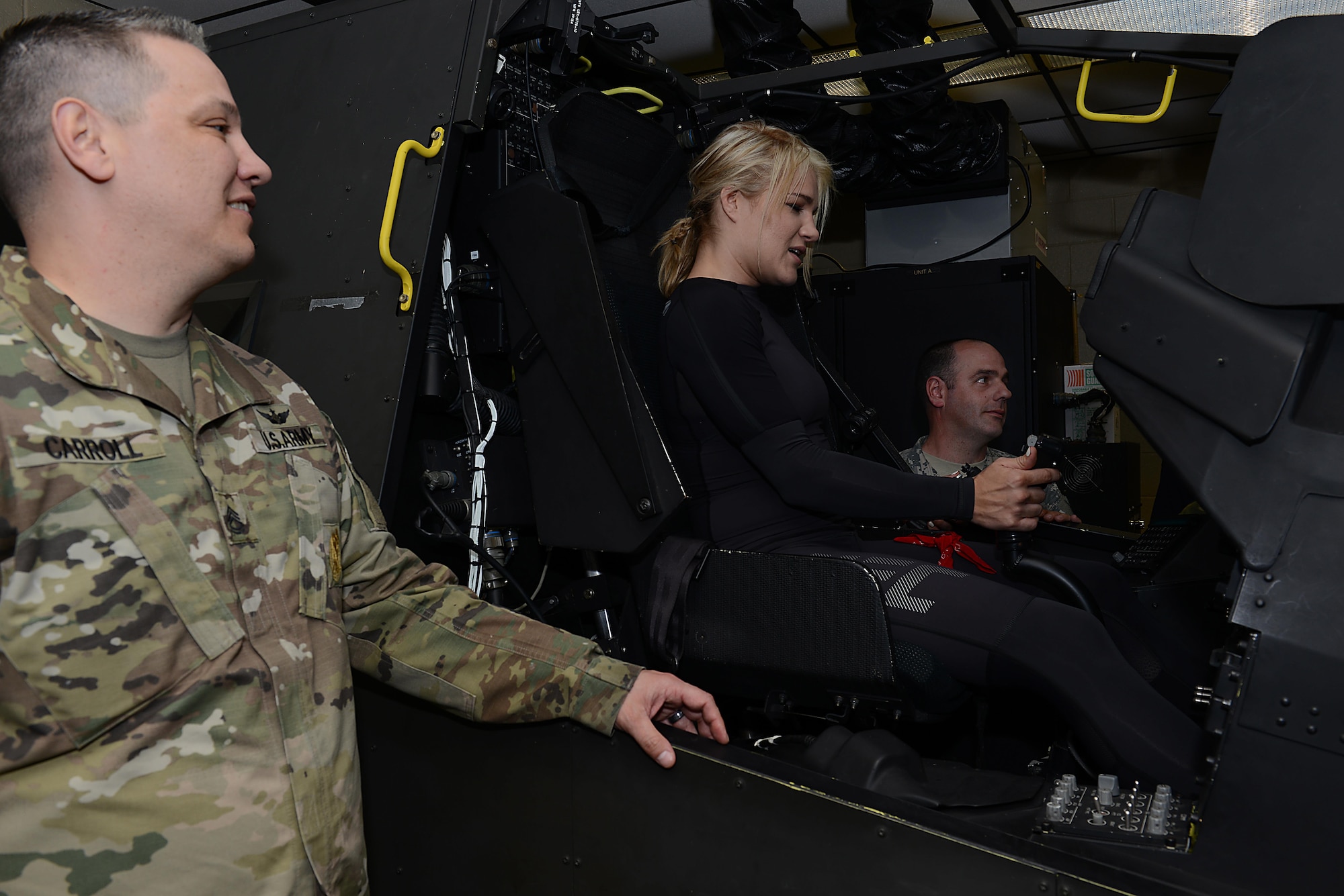 U.S. Army Sgt. 1st Class Robert Carroll, Alpha Company, 210th Aviation Regiment, 128th Aviation Brigade first sergeant, and Staff Sgt. Robert McRee, brigade instructor, provide guidance to Felice Herrig, UFC strawweight fighter, while operating an Apache helicopter simulator at Joint Base Langley-Eustis, Va., April 6, 2017. During the visit, UFC and hosts from MMAjunkie Radio met with U.S. service members to discuss their daily operations and to thank them for their service. (U.S. Air Force photo/Staff Sgt. Teresa J. Cleveland)