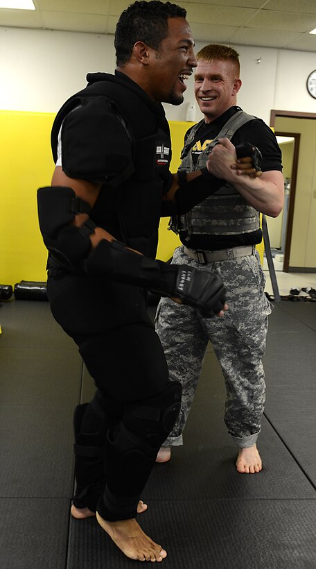 U.S. Army Staff Sgt. Richard Rometty, Charlie Company, 210th Aviation Regiment, 128th Aviation Brigade powertrain instructor, helps Kevin Lee, UFC lightweight fighter, to his feet after simulating a combative scenario at Joint Base Langley-Eustis, Va., April 6, 2017. During the demonstration, combative instructors demonstrated the differences between mixed martial arts training and Army combative training and how the two can be combined. (U.S. Air Force photo/Staff Sgt. Teresa J. Cleveland)