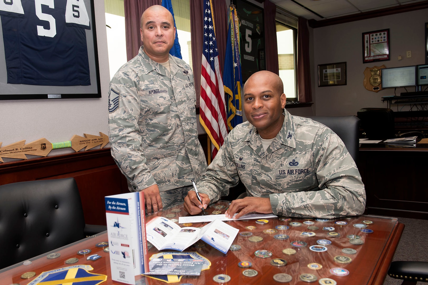 Col. Roy Collins, 37th Training Wing commander (seated) signs a contribution slip for the Air Force Assistance Fund as Master Sgt. Joseph Aponte, 323rd Training Squadron military training instructor and project officer for the 37th TRW AFAF campaign, looks on April 10, at Joint Base San Antonio-Lackland. The AFAF campaign is comprised of four charities, Air Force Villages Inc., Air Force Aid Society Inc., Air Force Enlisted Village Inc. and the General and Mrs. Curtis E. LeMay Foundation, which solely assists active duty, reserve and retired Airmen and their families. The various charities provide low to no-cost retirement homes for Airmen and family members, emergency funds and travel arrangements, scholarships, grants and more. (U.S. Air Force photo by Staff Sgt. Marissa Garner)