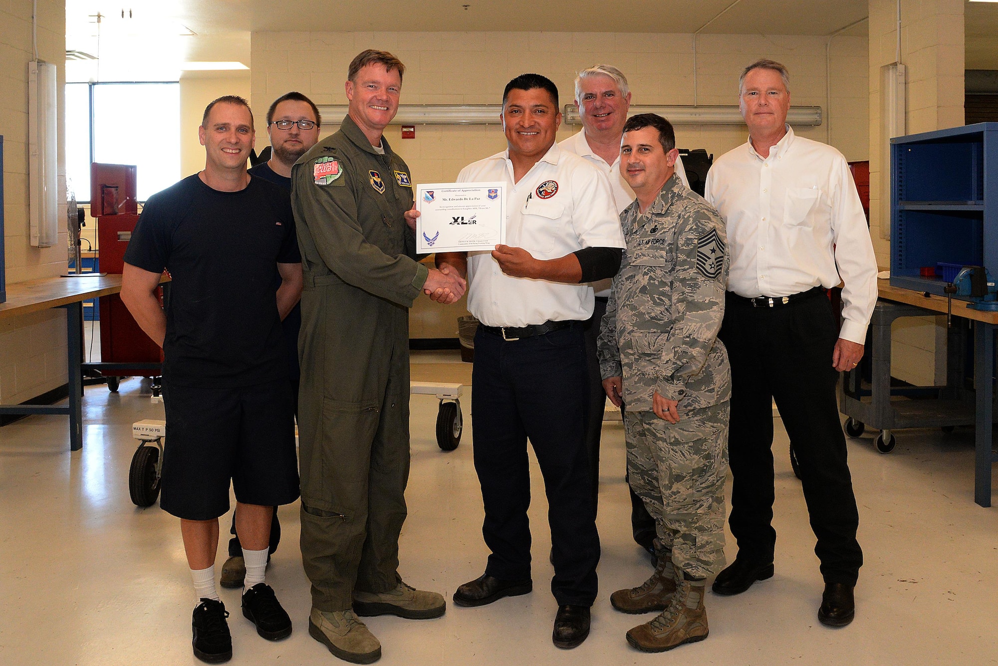 Edwardo De La Paz, 47th Maintenance Directorate aircrew egress shop supervisor (center), accepts the “XLer of the Week” award from Col. Thomas Shank, 47th Flying Training Wing commander (left), and Chief Master Sgt. George Richey, 47th FTW command chief (right), on Laughlin Air Force Base, Texas, April 4, 2017. The XLer is a weekly award chosen by wing leadership and is presented to those who consistently make outstanding contributions to their unit and Laughlin. (U.S. Air Force photo/Airman 1st Class Daniel Hambor)