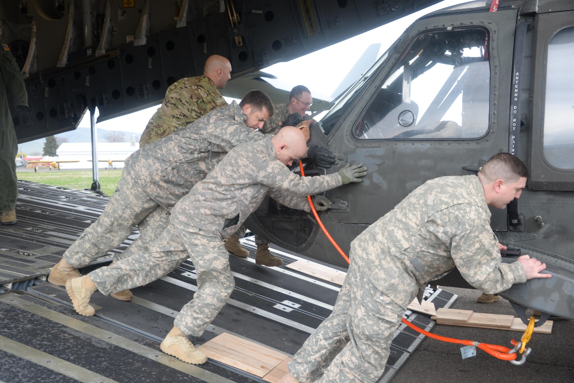 Members of the United States Army Air Ambulance Detachment, part of the 16th Combat Aviation Brigade, unload a UH-60 Black Hawk helicopter from a C-17 Globemaster III April 7 at Yakima Training Center, Washington. The joint training mission focused on the two units teaching and learning from one another about helicopter loading techniques. (U.S. Air Force photo / 2nd. Lt. Sarah Johnson)
