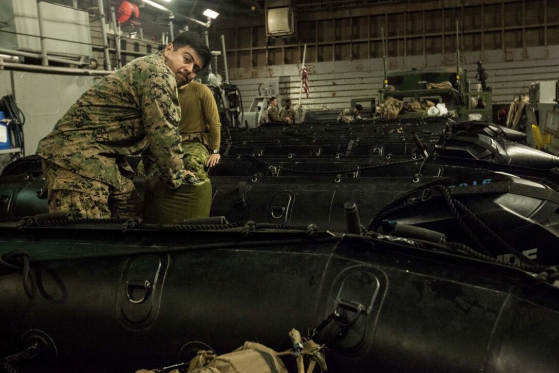 Marines with Fox Company, Battalion Landing Team, 2nd Battalion, 5th Marine Regiment, 31st Marine Expeditionary Unit, waterproof gear in a Combat Rubber Raiding Craft aboard the USS Green Bay (LSD 20), in preparation for a boat raid at Kin Blue Training Area, Okinawa, Japan, Mar. 22, 2017. Fox Co., BLT 2/5 conducted the boat raid during Certification Exercise as a part of the 31st MEU's 17.1 Spring Patrol. As the Marine Corps' only continuously forward-deployed unit, the 31st Marine Expeditionary Unit's air-ground-logistics team provides a flexible force, ready to perform a wide range of military operations, from limited combat to humanitarian assistance operations, throughout the Indo-Asia-Pacific region. (U.S. Marine Corps photo by Lance Cpl. Jorge A. Rosales/ Released) 