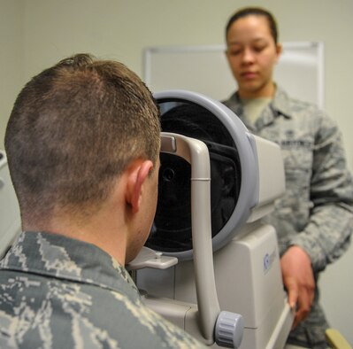 U.S. Air Force Staff Sgt. River Carson, 8th Medical Operations Squadron public health technician, applies his forehead to the auto refractometer as Senior Airman Kiara Warren, 51st Aerospace Medicine Squadron optometry technician, operates the machine at Kunsan Air Base, Republic of Korea, March 24, 2017. The auto refractometer measures the curvature of the eye and allows a scan to give a baseline prescription for eyes. (U.S. Air Force photo by Senior Airman Colville McFee/Released
