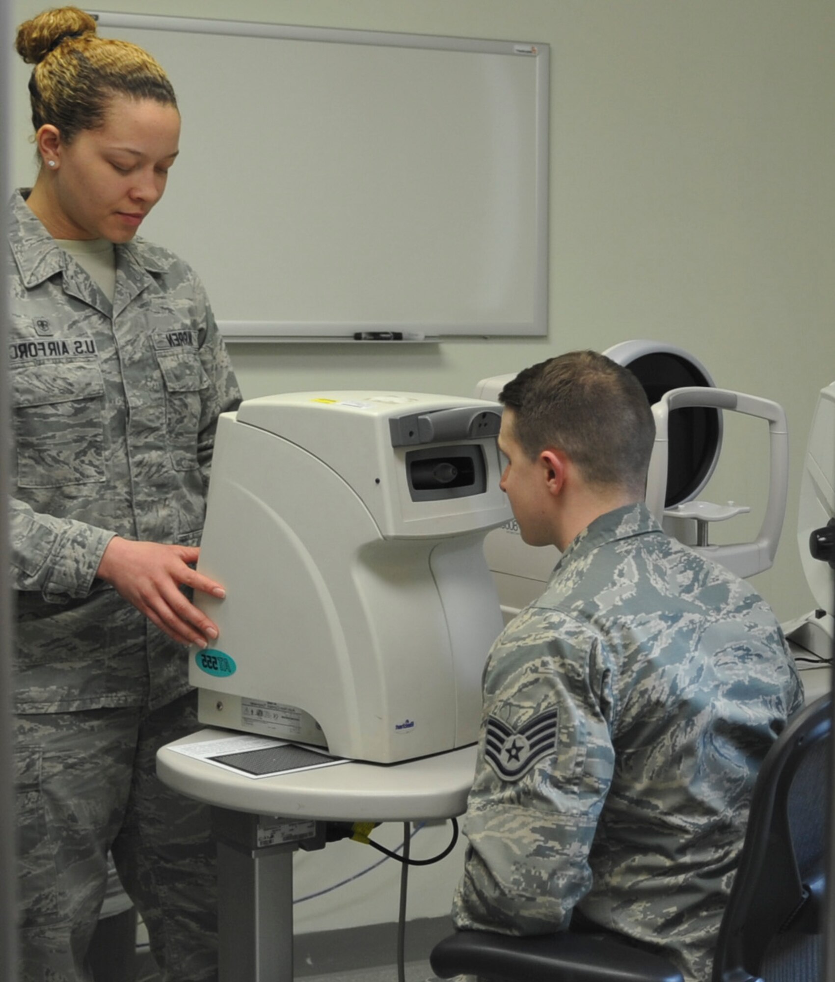 U.S. Air Force Senior Airman Kiara Warren, 51st Aerospace Medicine Squadron optometry technician, left, operates the non-contact tonometer while Staff Sgt. River Carson, 8th Medical Operations Squadron public health technician, applies his forehead to the machine at Kunsan Air Base, Republic of Korea, March 24, 2017. The non-contact tonometer checks the pressure of the eye by blowing air into the eye to flatten the cornea to measure intraocular pressure. (U.S. Air Force photo by Senior Airman Colville McFee/Released)