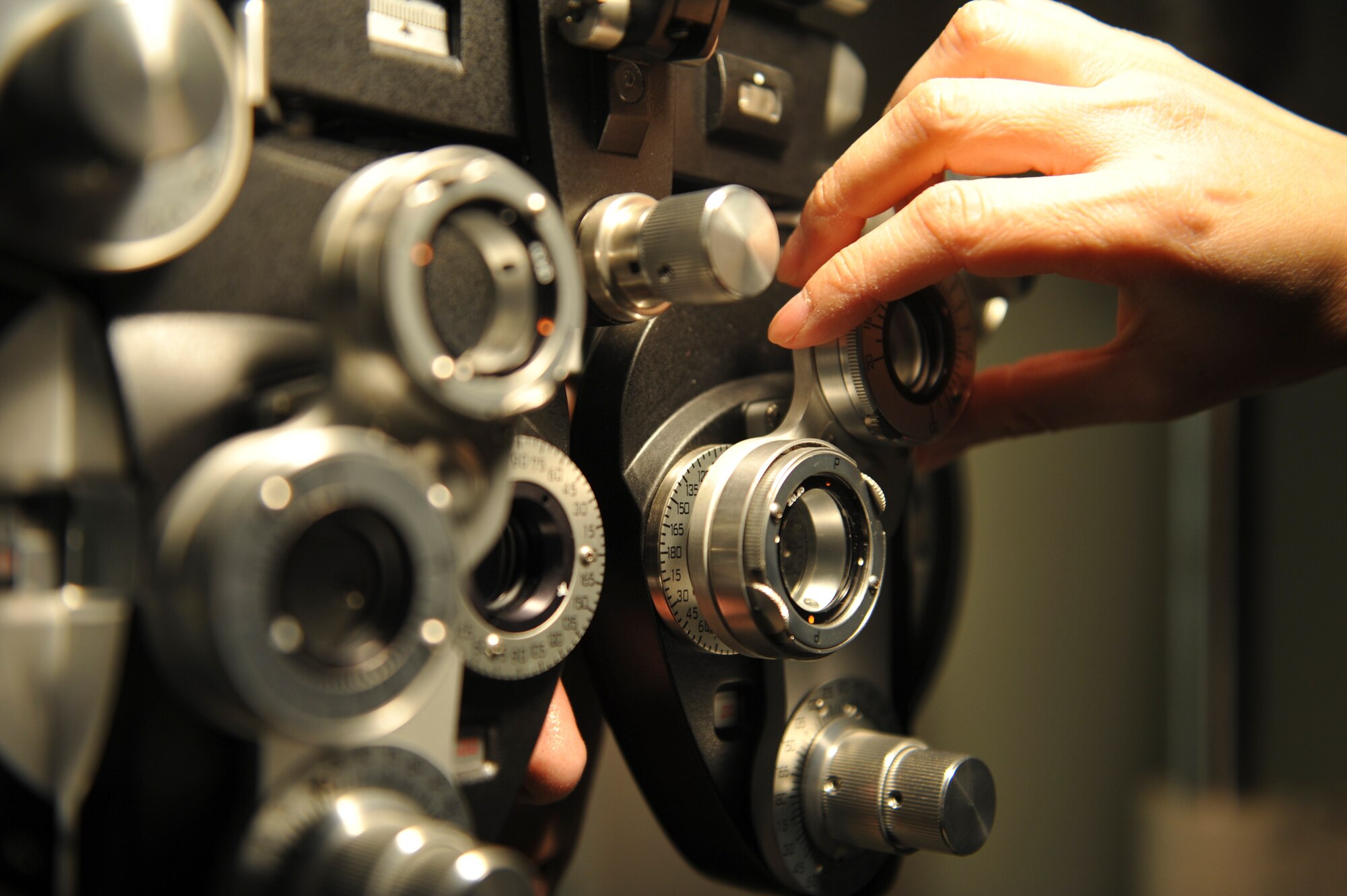 U.S. Air Force Staff Sgt. River Carson, 8th Medical Operations Squadron public health technician, left, stares at a letter chart as Maj. See Vang, 51st Aerospace Medicine Squadron optometry flight commander, changes lenses on the phoropter on his eyes at Kunsan Air Base, Republic of Korea, March 24, 2017. The phoropter checks for refractive errors in the eyes and assists in eye glass prescriptions.  (U.S. Air Force photo by Senior Airman Colville McFee/Released)