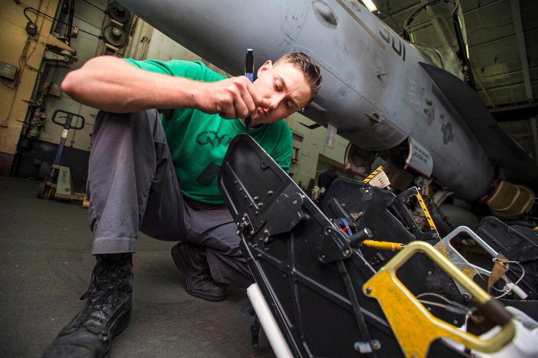 Navy Petty Officer 2nd Class Eric Christy performs anti-corrosion maintenance on an ejection seat for an F/A-18F Super Hornet in the hangar bay of the aircraft carrier USS Dwight D. Eisenhower in the Atlantic Ocean, April 2, 2017. Christy is an aviation structural mechanic. Navy photo by Seaman Zachary A. Sleeper