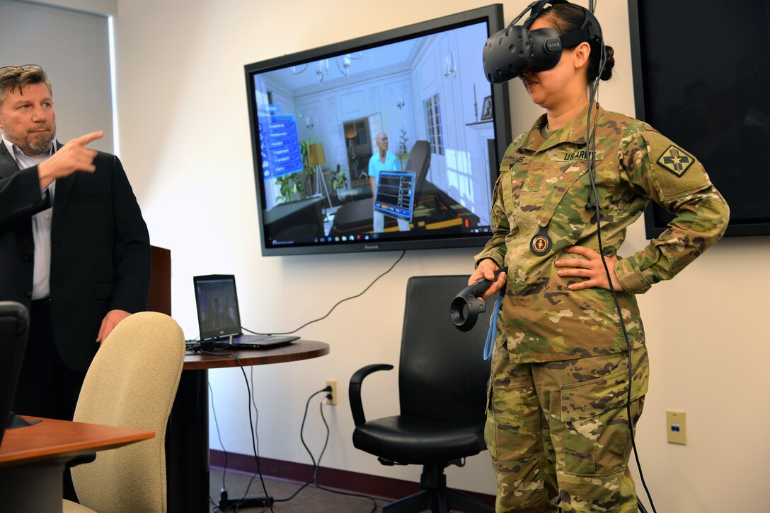 Maj. Jean Williams, right, Medical Education Training Campus Department of Combat Medic Training branch chief, participates in a demonstration of the Virtual Education System under the direction of Robert Moore, CEO of Virtual Education Systems, at Heritage Hall at Joint Base San Antonio-Fort Sam Houston April 1. VES is a virtual reality based training platform in which the learner interacts with a virtual patient in various situations, including at a home, an ambulance and a hospital room.